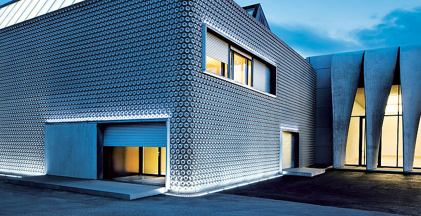 Mehrere Einbruchschutz-Rolltore vom Typ wES 48 beim Eingang und den Fenstern eines modernen Firmengebäudes