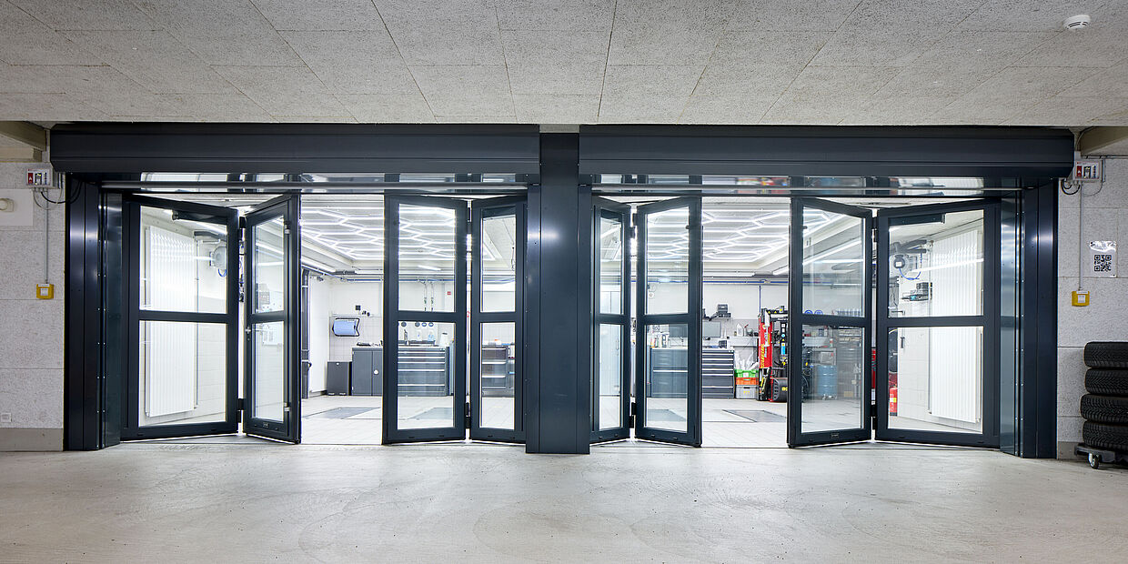 Automatisiertes Falltor 63 vollverglast, kombiniert mit Brandschutzvorhang von Wolfisberg Tor-Technik AG.