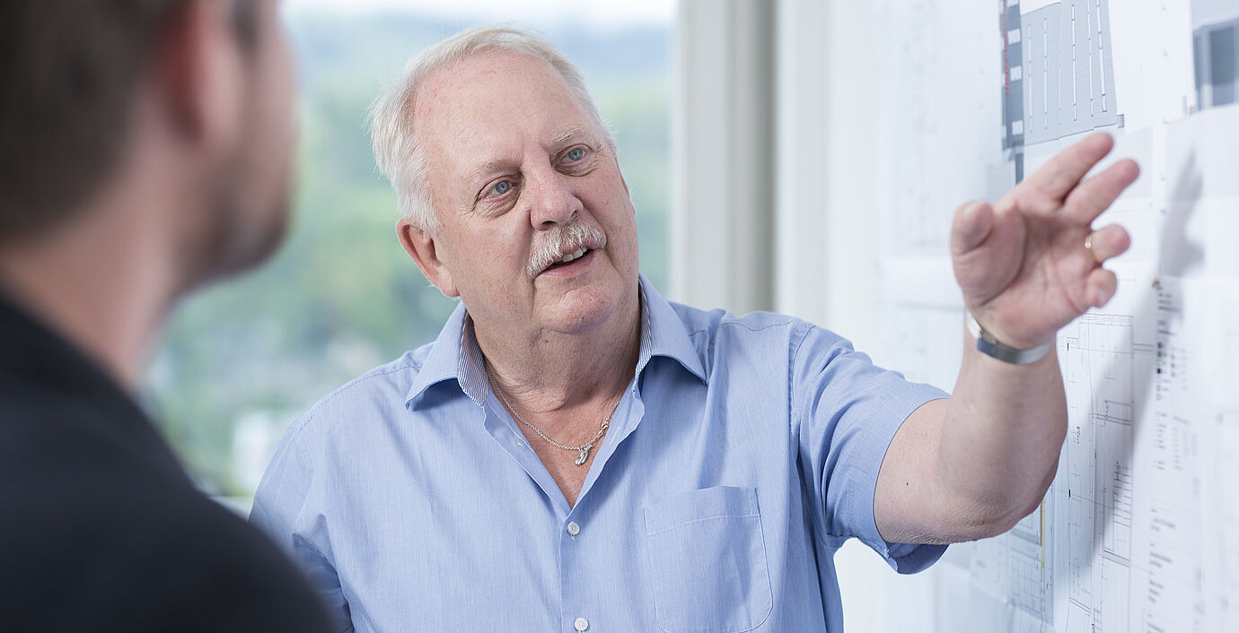 Urs Wolfisberg bei der Besprechung einer Gebäudeplanung mit einem Architekten an einem Whiteboard